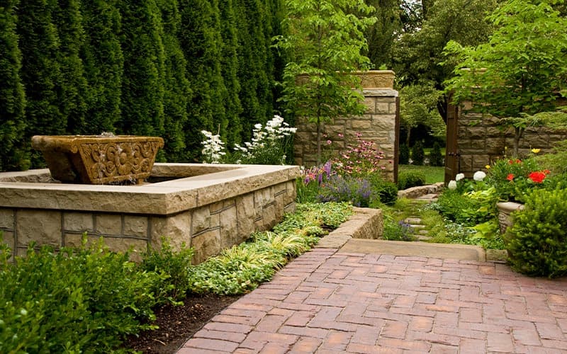 Brick path, stone walls, and layered planting in a Franz Witte landscape